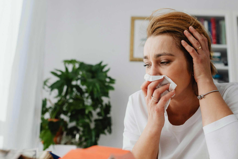 A woman sneezing from a cold or allergies