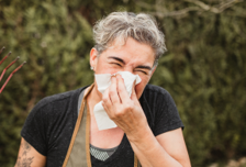 A man sneezing using tissue