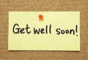 A sticky note on a cork board that reads "get well soon"