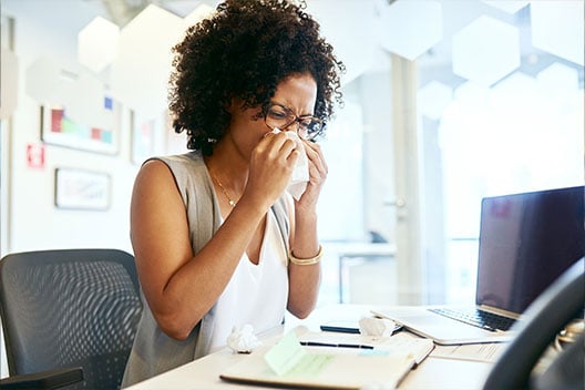 Woman using Kleenex® Trusted Care® Tissue to clean up mess from a sneeze
