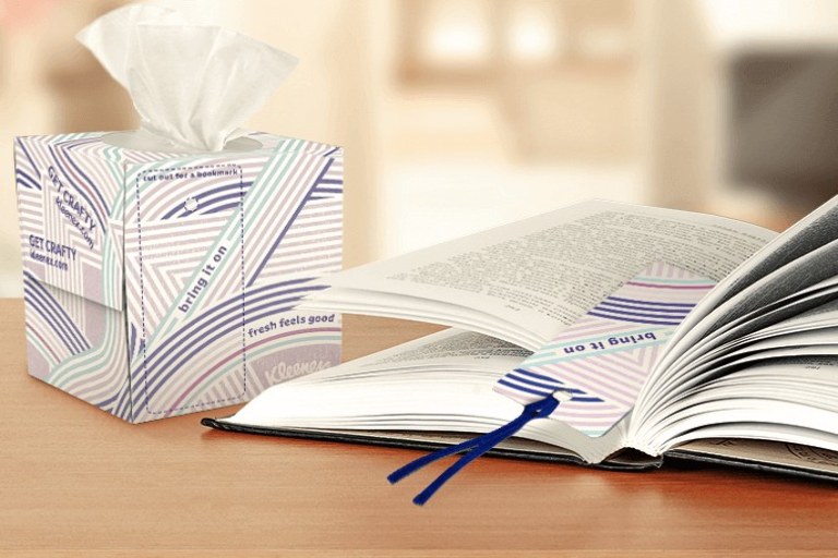Tissue box sitting next to an open book on a table